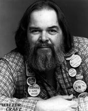 photo of Walter Craft wearing a checked flannel shirt, lots of buttons, and a big smile through his bushy beard