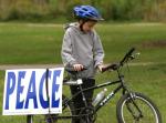 photo of a boy on his bike next to a sign that reads "Peace"