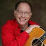 Red Grammer holding acoustic guitar and smiling at camera