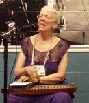 photo of Sally Campbell in concert, singing and strumming an autoharp.