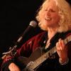 photo of Denise Jordan Finley singing & playing guitar in concert