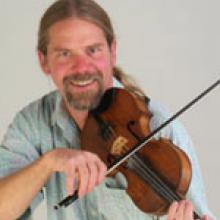 photo of Kevin McMullin playing fiddle and smiling