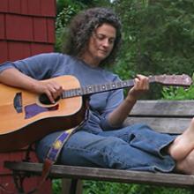 photo of Sara Thomsen sitting outside playing guitar